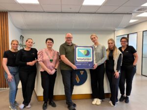 Smilende ansatte og ordfører med miljøfyrtånr plaketten
